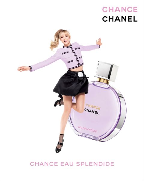 Eine Frau im modischen Outfit springt freudig vor einer großen Flasche Chanel Chance Eau Splendide. Die Flasche ist lila mit silbernem Deckel. Der Text lautet „CHANCE CHANEL“ und „CHANCE EAU SPLENDIDE“.