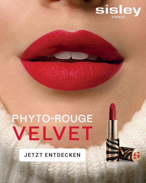 Nahaufnahme der Lippen einer Frau mit leuchtend rotem Lippenstift. Darunter ist eine Lippenstifthülse mit Zebramuster zu sehen. Der Text lautet „Sisley Paris Phyto-Rouge Velvet“. Jetzt entdecken.