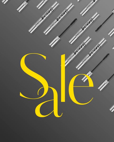 Silberne Mascara-Tuben und -Stäbchen sind diagonal auf einem grauen Hintergrund mit Farbverlauf angeordnet; in der Mitte steht in großem gelben Text „Sale.“.