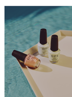 Drei Flaschen OPI-Nagellack, zwei aufrecht stehende (weiß und hellgrün) und eine pfirsichfarbene, auf der Seite liegende, werden auf einem Tablett am Rand eines Pools mit schimmerndem blauem Wasser präsentiert.