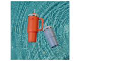 Zwei isolierte Becher, einer orangefarben mit Henkel und einer hellblau, schwimmen auf der Oberfläche eines Schwimmbeckens mit klarem, plätscherndem Wasser.