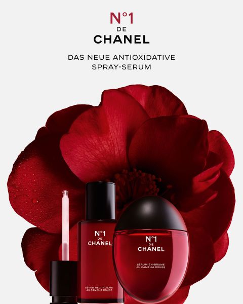 Drei rote No.1 de Chanel-Hautpflegeprodukte werden vor einer großen roten Kamelienblüte präsentiert, über dem Bild steht der Text „N°1 DE CHANEL DAS NEUE ANTIOXIDATIVE SPRAY-SERUM“.