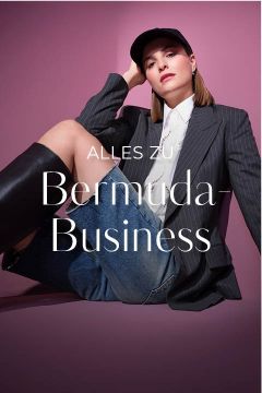 Eine Frau posiert selbstbewusst vor einem rosafarbenen Hintergrund und trägt einen Nadelstreifenblazer, ein weißes Hemd, Bermudashorts aus Jeansstoff, schwarze kniehohe Stiefel und eine schwarze Kappe. Der überlagerte Text lautet "ALLES ZU Bermuda-Business".