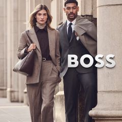 Eine Frau in einem beigen Kostüm und ein Mann in einem grauen Anzug stehen neben dem BOSS-Logo.