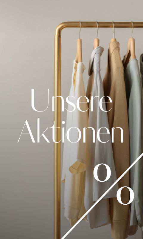 Kleidung in neutralen Tönen hängt an einem goldenen Kleiderständer vor einem beigen Hintergrund. Der weiße Text lautet "Unsere Aktionen" mit einem großen Prozent-Symbol darunter, das auf einen Verkauf oder eine Werbeaktion hindeutet.