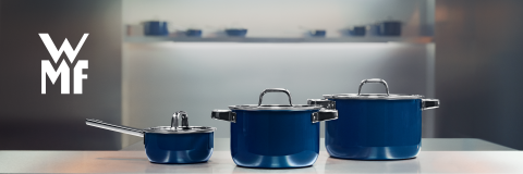 Drei glänzende blaue Töpfe mit silbernen Deckeln und Griffen stehen auf einer Küchentheke, mit dem WMF-Logo auf der linken Seite und einem verschwommenen Küchenhintergrund.