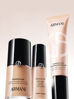 Drei Make-up-Produkte aus der „Luminous Silk“-Serie von Giorgio Armani: Foundation, Concealer und Highlighter-Primer, in eleganten Flakons mit schwarz-beiger Verpackung.