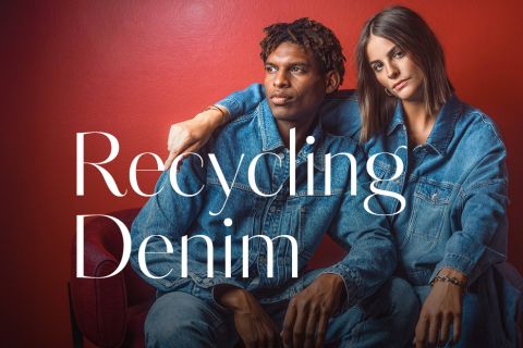 Zwei Personen in Jeansoutfits sitzen nebeneinander vor einer roten Wand; über das Bild ist der Schriftzug „Recycling Denim“ gelegt.