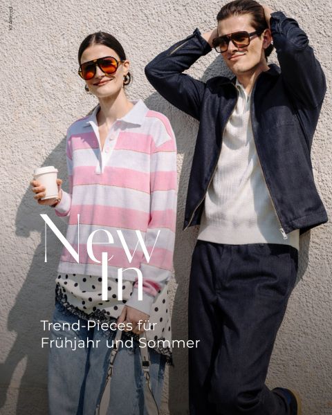 Eine elegante Frau in einem rosa gestreiften Hemd und ein Mann in einer marineblauen Jacke posieren mit Sonnenbrille in der Sonne. Text: "New In Trend-Pieces für Frühjahr und Sommer.