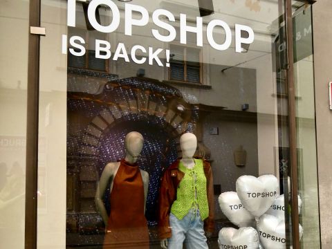 Schaufenster mit "TOPSHOP IS BACK!"-Schild, zwei Schaufensterpuppen in trendigen Outfits und weißen herzförmigen Luftballons mit dem Aufdruck "TOPSHOP".