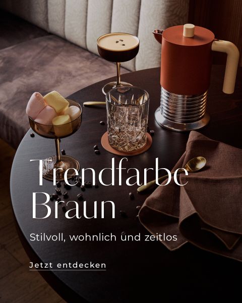 Ein runder Tisch mit Getränken in Brauntönen, Marshmallows, einer Stoffserviette, goldenem Besteck und verstreuten Kaffeebohnen. Der Text wirbt mit „Trendfarbe Braun“.