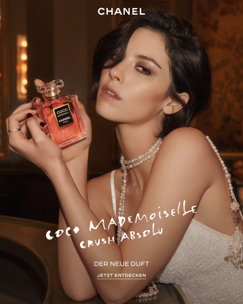 Eine Frau in einem perlfarbenen Kleid hält einen Flakon des Parfüms „Chanel Coco Mademoiselle“ in der Hand; auf dem Bild sind der Schriftzug „Chanel“ sowie Angaben zum Duft zu sehen.