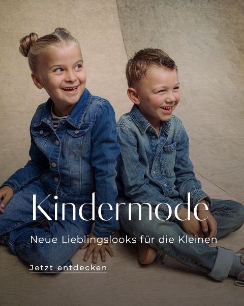 Zwei lächelnde Kinder in Jeansoutfits sitzen auf einem Holzboden. Ein Text auf Deutsch wirbt für Kindermode und lädt die Betrachter dazu ein, neue Lieblingslooks zu entdecken.