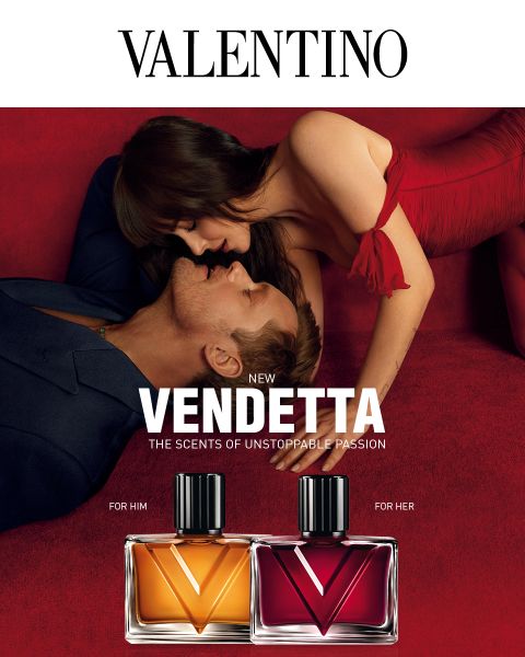 Ein Mann und eine Frau in eleganter Kleidung umarmen sich auf rotem Samt neben den Parfümflakons „Valentino Vendetta“, von denen einer mit „For Him“ und der andere mit „For Her“ beschriftet ist.