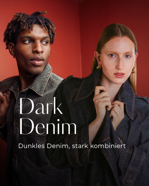 Ein Mann und eine Frau tragen dunkle Jeansjacken vor rotem Hintergrund. Der Text lautet: „Dark Denim. Dunkles Denim, stark kombiniert.“.