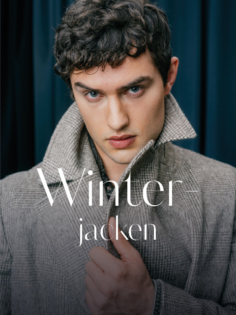 Ein Mann, der einen grauen, gemusterten Mantel trägt, auf dem der Schriftzug „Winterjacken“ aufgedruckt ist.