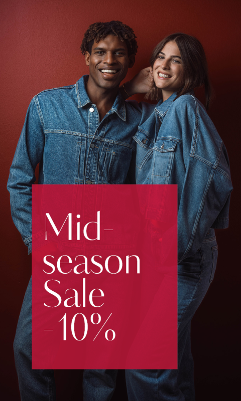 Zwei Personen in Jeansoutfits stehen lächelnd vor einer roten Wand. Auf dem Bild steht: „Saison-Zwischenverkauf – 10 %“.